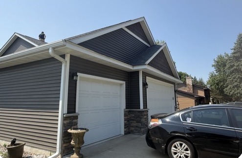Existing white steel garage doors on a dark-sided Minnesota home before the AI redesign